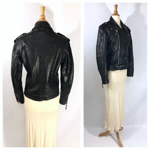May include: Black leather motorcycle jacket with a zipper closure, multiple pockets, and a belt at the waist.