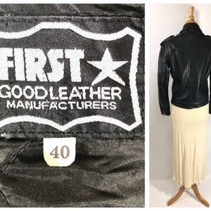 May include: Black leather jacket with a star and the text "FIRST GOODLEATHER MANUFACTURERS" on the label. The jacket has a size tag that says "40".