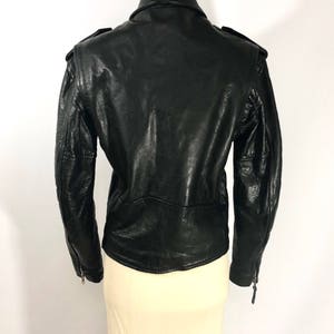 May include: Black leather jacket with a zipper closure and a stand-up collar. The jacket has a fitted silhouette and features a quilted design on the back.