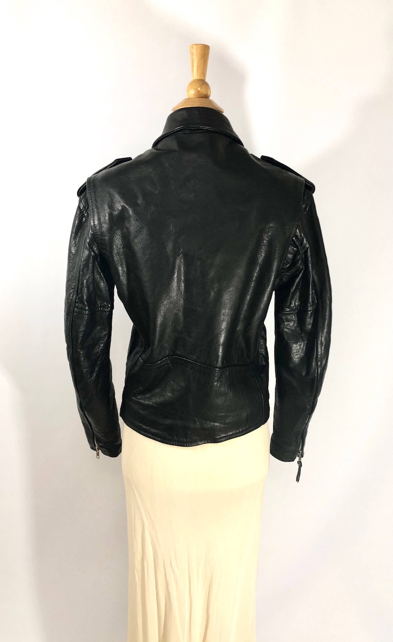 May include: Black leather jacket with a zipper closure and a stand-up collar. The jacket has a fitted silhouette and features a quilted design on the back.
