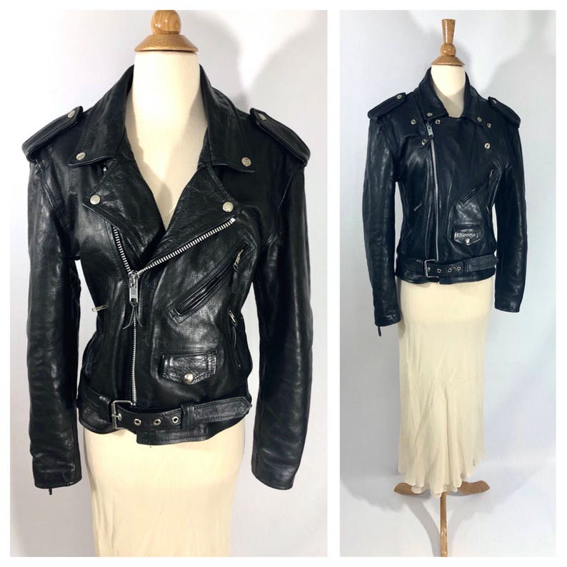 May include: Black leather motorcycle jacket with a zipper closure, multiple pockets, and a belt at the waist.