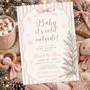 May include: A rectangular baby shower invitation card featuring a light pink striped background, a decorative frame with a bow, and green pine branch illustrations. The text reads: Baby it's cold outside! Please join us for a baby shower in honor of Charlotte Rose, Saturday, January 18, 2:00 PM, The Willow House, 306 Maple Ridge Drive, Richmond, Virginia 23233, RSVP to Kayla by January 8th, 804.555.7831 or kaylah@email.com, registered at Amazon & Target.