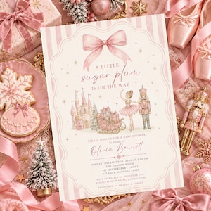 May include: A rectangular baby shower invitation card featuring a pink striped background, a large bow at the top, and illustrations of a castle, a sleigh with gifts, a ballerina, and a nutcracker. The text reads A LITTLE sugar plum IS ON THE WAY.