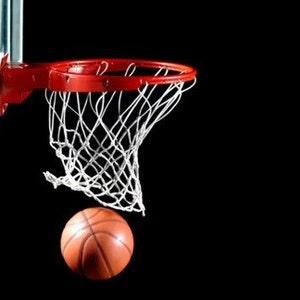 May include: A basketball is about to go through a red basketball hoop with a white net. The hoop is attached to a backboard.