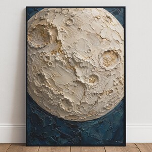 Op de afbeelding: Een ingelijst kunstwerk aan de muur met een gestructureerde, impasto-stijl afbeelding van de maan in crèmekleurige en gebroken witte tinten met bladgoudaccenten, tegen een diep marineblauwe achtergrond met dikke, zichtbare penseelstreken.