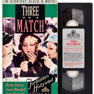May include: A VHS tape of the film Three on a Match from the Forbidden Hollywood series. The cover features three women in hats smoking, with the text In Glorious Black & White, Three on a Match, and names Bette Davis, Joan Blondell, and Ann Dvorak.