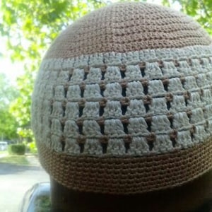 Puede incluir: Un gorro de punto marrón y blanco con un diseño estampado.