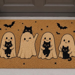 May include: A rectangular tan coir doormat featuring a printed design of four light beige ghosts and four black cats. The ghosts are depicted with simple facial features, and the black cats are shown in various poses. Small black stars and bats are scattered across the mat.