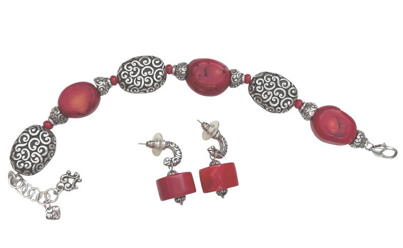 May include: A jewelry set featuring a bracelet and matching earrings. The bracelet has red oval beads and silver-colored, patterned beads. The earrings have red rectangular beads and silver-colored, curved posts. The set is on a white background.