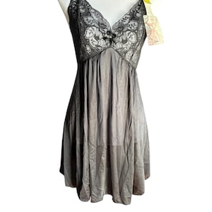 May include: A gray slip dress with black lace detailing on the bodice. The dress has thin straps and a flowing skirt. A tag is attached to the strap. The dress is displayed on a mannequin.