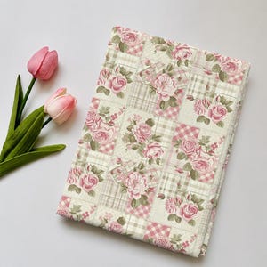 May include: A rectangular fabric piece featuring a patchwork design of alternating squares with pink rose floral patterns and beige plaid motifs, accompanied by two pink tulip flowers with green stems and leaves on the side.