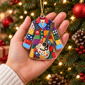 Könnte beinhalten: Ein flacher, mantelartiger Weihnachtsbaumschmuck mit einem bunten Patchwork-Design aus Blumenmustern, Sternen und einem schwarz-weiß karierten Quadrat. Eine helle akustische Gitarre ist mittig auf der Vorderseite mit einem kleinen roten Herz abgebildet.