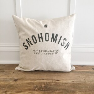 May include: A beige throw pillow with black text that reads "Snohomish" and the coordinates "47° 55'36.2316"N 122° 7'7.8348"W".