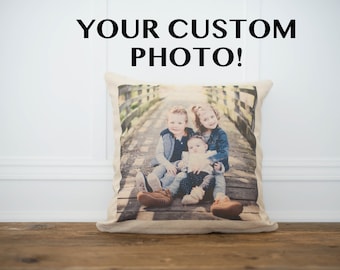 May include: A beige pillow with a photo of three children sitting on a wooden bridge. The children are smiling and wearing casual clothing. The text "YOUR CUSTOM PHOTO!" is printed above the pillow.