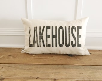 May include: A white pillow with black text that reads "LAKEHOUSE".