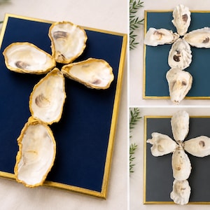 May include: A rectangular wall art piece featuring a cross arrangement of five natural oyster shells with gold-painted edges, mounted on a solid dark blue background within a thin gold frame, presented in three different color variations.