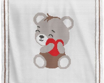 May include: A crocheted baby blanket with a gray bear holding a red heart. The blanket has a white background with a brown border.