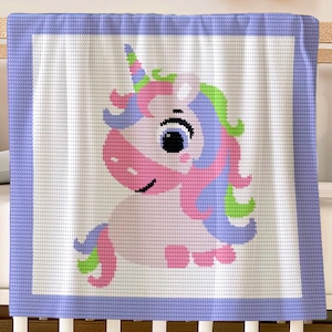 Puede incluir: Una manta de bebé de crochet blanco con un borde morado presenta un unicornio rosa y morado con un cuerno y una crin verdes.