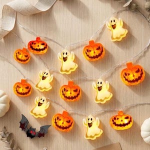May include: A string of LED lights featuring alternating orange jack-o'-lantern pumpkins and white ghosts. The pumpkins have carved facial expressions, and the ghosts have smiling faces. The lights are connected by a thin, clear wire.