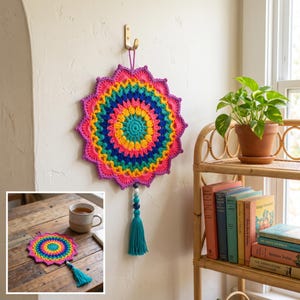 Pode incluir: Uma tapeçaria de parede circular em crochê multicolorido com um padrão de mandala vibrante em tons de rosa, amarelo, azul e verde. A peça inclui uma borla pendente azul-petróleo com contas azuis e brancas, suspensa num gancho dourado.
