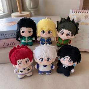 May include: A collection of six plush dolls featuring stylized anime-inspired characters with distinct hair colors including black, yellow, dark green, red, white, and black, each wearing unique outfits and displaying varied facial expressions.