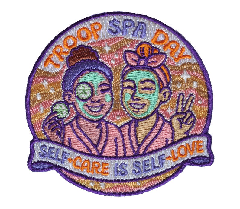 May include: A circular embroidered patch featuring two figures in pink robes with green facial masks. The text TROOP SPA DAY is arched at the top, and a banner at the bottom reads SELF-CARE IS SELF-LOVE. The background is a wavy peach and gold pattern.