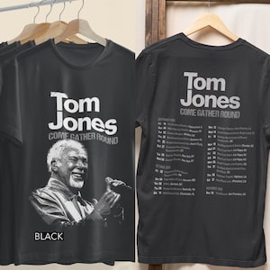 May include: A black t-shirt featuring a white graphic of Tom Jones singing on the front with the text Tom Jones Come Gather Round. The back of the shirt displays a list of tour dates for September, October, and November 2026 in white text.