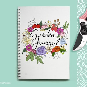 May include: A white spiral bound journal with a floral design and the text "Garden Journal" in black cursive lettering.