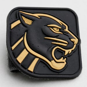 May include: A square-shaped black rubber patch featuring a raised, gold-colored relief design of a snarling panther head in profile. The panther has detailed ears, eyes, and whiskers, with a textured border and a gray hook-and-loop backing visible.