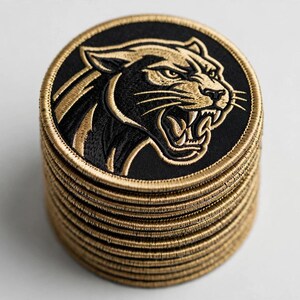 May include: A vertical stack of circular embroidered patches, each featuring a black background with a gold-colored panther head design. The panther is depicted in profile with an open mouth, bared teeth, and detailed gold stitching. Each patch has a thick gold border.
