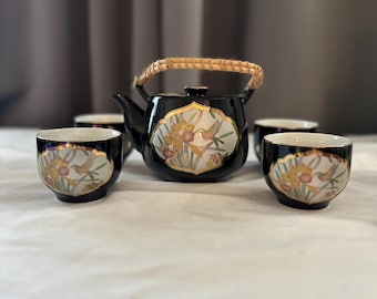 Japanese black ceramic tea set featuring a woven bamboo handle and delicate gold floral and hummingbird or bird motifs.