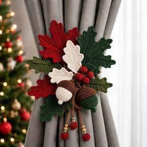 May include: A crochet curtain tieback featuring a cluster of red and green oak leaves, two white oak leaves, two acorns in brown and white or green, and small red berries. Three dangling cords with red crochet spheres and gold beads hang below.