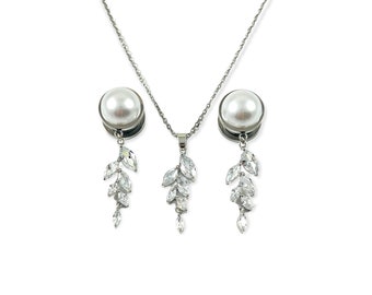 May include: A silver necklace and earrings set with a pearl pendant and dangling crystal accents. The pendant and earrings feature a leaf design with clear crystals.