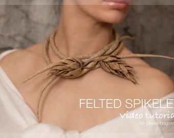 May include: A woman wears a brown felt necklace with two large felt wheat stalks. The necklace is called "Felted Spikelet Video Tutorial" by Diana Nagorna.