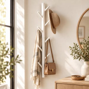 Puede incluir: Un perchero vertical blanco con múltiples ganchos angulados que se extienden desde el poste central. Un sombrero de fieltro beige cuelga del gancho superior, una bufanda de cuadros beige y gris en el medio y un bolso de cuero beige abajo.