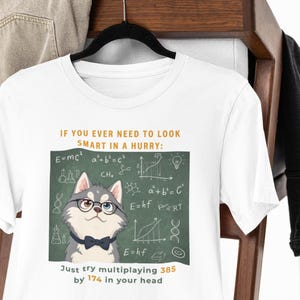 Può includere: Una t-shirt bianca con la grafica di un husky grigio e bianco che indossa occhiali neri e un papillon blu scuro. Lo sfondo è una lavagna verde con formule scientifiche bianche e il testo: IF YOU EVER NEED TO LOOK SMART IN A HURRY: Just try multiplaying 385 by 174 in your head.
