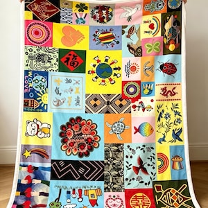 Puede incluir: Una manta rectangular con un vibrante diseño de patchwork que incluye diversas ilustraciones como un gato de la suerte, un dragón rojo, un globo terráqueo con niños, una mariquita, una tortuga, un pez colorido y varios patrones florales y geométricos.