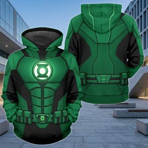 May include: A green and black hooded sweatshirt featuring a graphic print of a superhero costume. The front displays a glowing circular emblem on the chest and a utility belt design at the waist. The back shows a matching green and black pattern.