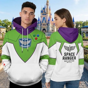 Könnte beinhalten: Zwei Kapuzenpullover mit Buzz Lightyear-Design. Der vordere Pullover ist grün, weiß und lila mit einem Star Command-Logo und drei farbigen Knöpfen. Der hintere Pullover ist weiß, grün und lila mit dem Schriftzug Space Ranger.
