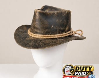 May include: A distressed dark brown leather hat with a pinched crown and a wide brim. A thick, light tan braided rope band encircles the base of the crown, featuring a decorative knot detail on the side. The leather has a weathered, worn finish.