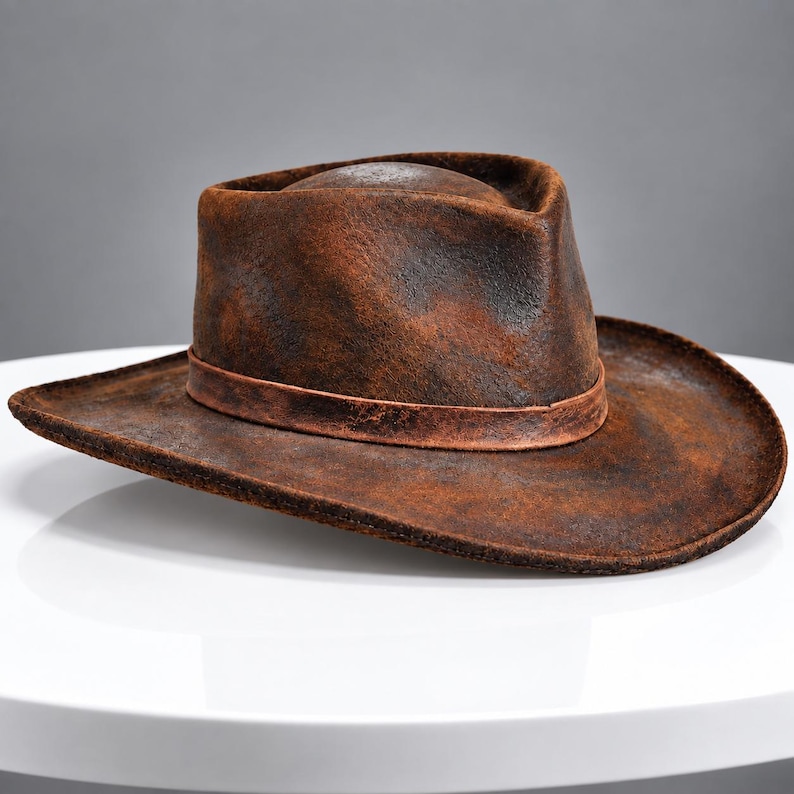 May include: A distressed brown fedora hat with a textured, weathered finish. The hat features a pinched crown and a wide, slightly curved brim, accented by a matching brown band encircling the base of the crown, creating a rugged appearance.