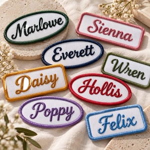 Puede incluir: Una colección de parches bordados con nombres en formas ovaladas y rectangulares con centros de tela blanca. Los parches incluyen los nombres Marlowe, Sienna, Everett, Wren, Daisy, Hollis, Poppy y Felix, cada uno cosido con hilo de color a juego.