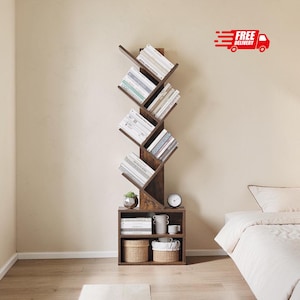 May include: A dark brown wooden tree-shaped bookshelf with multiple angled shelves holding books, a small potted succulent, a round clock, white ceramic containers, and two woven baskets in the base storage compartment.
