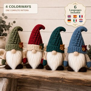 May include: Four crocheted gnomes with long white beards, wearing tall textured hats in olive green, red, dark teal, and blue. Each hat features a small wooden button and a fabric leaf. Text reads 4 COLORWAYS ONE COMPLETE PATTERN and 6 Languages Included.