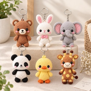 May include: A collection of six crocheted animal keychains featuring a brown bear, a white rabbit with a pink bow, a grey elephant with pink ears, a black and white panda, a yellow chick, and a brown and yellow giraffe, each with a metal ring.