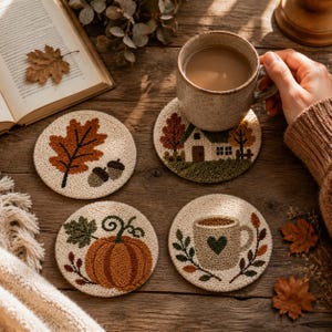 Könnte beinhalten: Vier runde Punch-Needle-Untersetzer mit herbstlichen Motiven: ein großes braunes Blatt mit zwei Eicheln, ein kleines Haus zwischen Bäumen, ein orangefarbener Kürbis mit grünen Blättern und eine beige Tasse mit einem dunkelgrünen Herz.