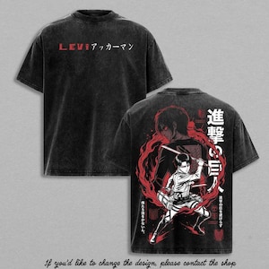 Op de afbeelding: Een zwart acid-wash t-shirt met een afbeelding op de voorkant met de tekst LEVIアッカーマン. De achterkant toont een gedetailleerde anime-illustratie van Levi Ackerman met zwaarden, omringd door rode cirkelvormige rook en Japanse karakters.
