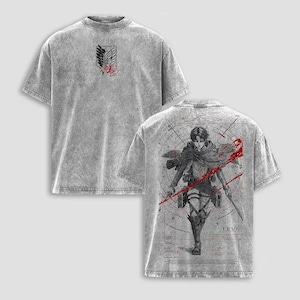 Pode incluir: Uma t-shirt cinzenta com efeito de lavagem ácida, apresentando um pequeno emblema na frente com asas e uma rosa. As costas exibem um grande gráfico da personagem Levi em uniforme militar com espadas, rodeado por traços vermelhos e linhas.