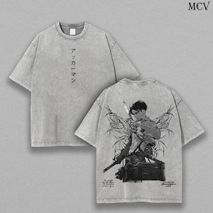 Puede incluir: Una camiseta gris con efecto lavado al ácido y texto en japonés en el pecho. La parte posterior muestra una detallada ilustración gráfica en blanco y negro de un personaje sosteniendo una espada con elementos alados y texto pequeño.