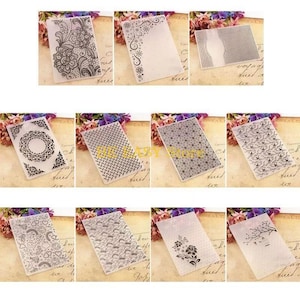 May include: A collection of twelve rectangular plastic embossing folders, each featuring a distinct raised pattern including floral lace, geometric grids, stars, swirls, and nature-inspired motifs, designed for creating textured impressions on paper crafts.